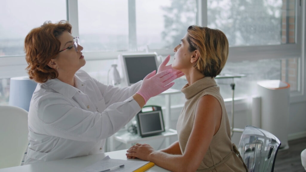 Lekarka pregleda kožu na licu žene tokom dermatološkog pregleda