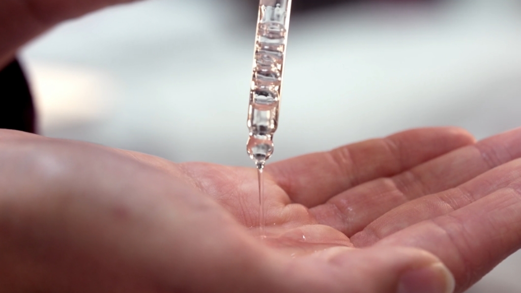 Osoba sipa retinol ili bakučiol serum u ruku