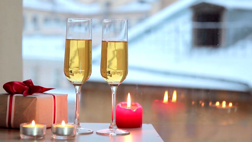 Poklon, sveće i dve čaše šampanjca na stolu