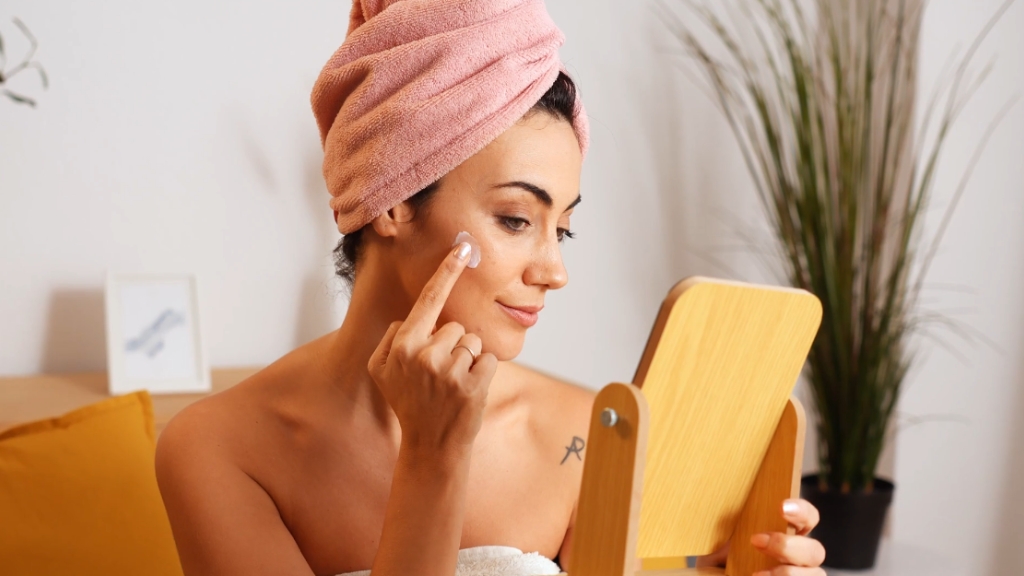 Žena nanosi SPF kremu na lice ispred ogledala