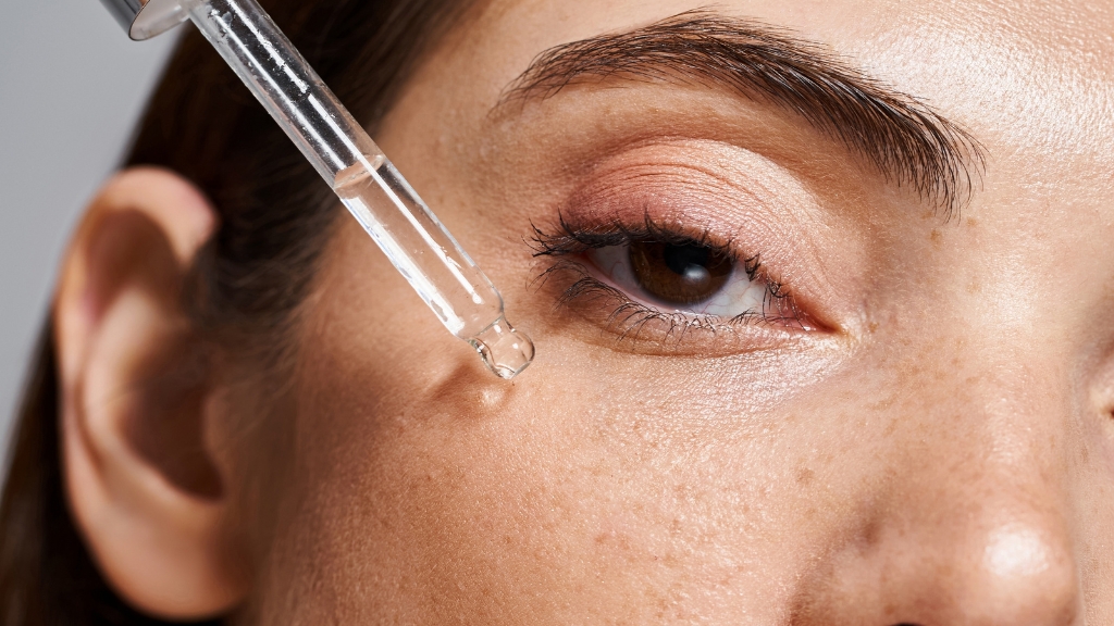 Žena pipetom nanosi serum na lice