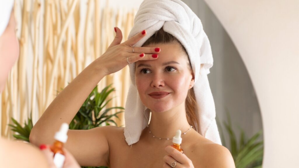 Žena nanosi serum na lice ispred ogledala