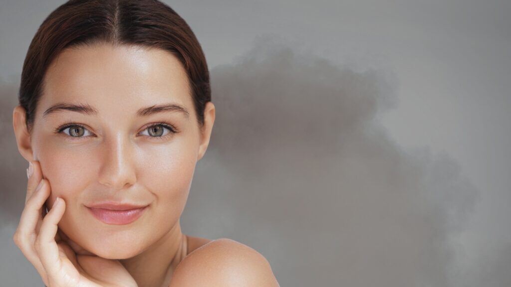 Žena sa čistom i negovanom kožom lica ispred zagađenog vazduha kao primer kako zaštititi kožu od zagađenja