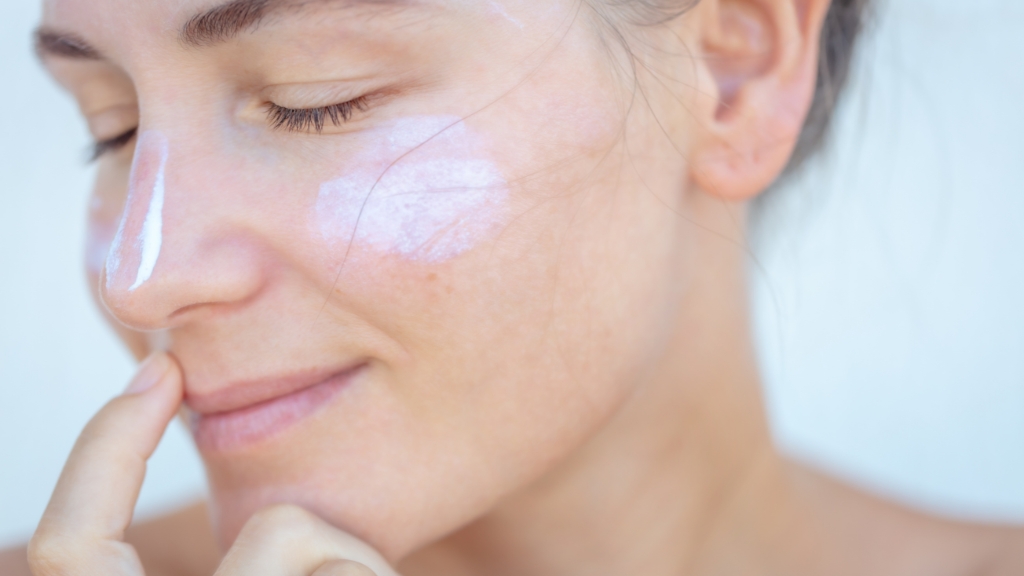 Žena nanosi SPF kremu na lice kao zaštitu kože od zagađenja i UV zraka