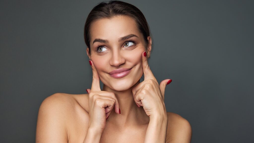 Žena lagano zateže kožu na obrazima prstima i pokazuje efekat zategnutog, glatkog lica