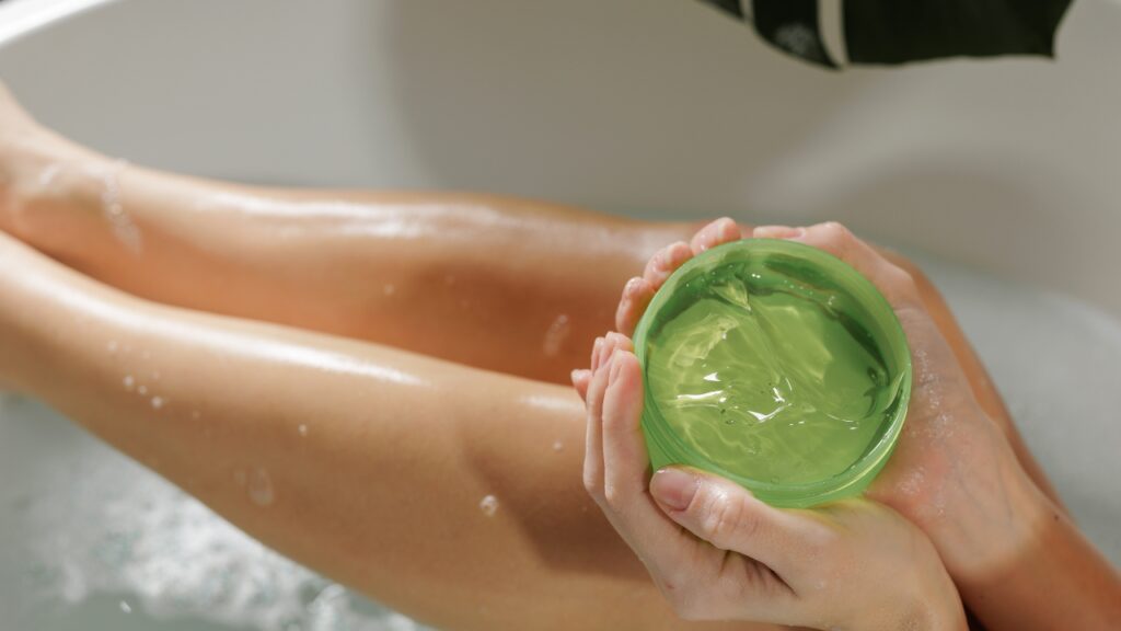 Osoba drži aloe vera gel pored nogu posle brijanja