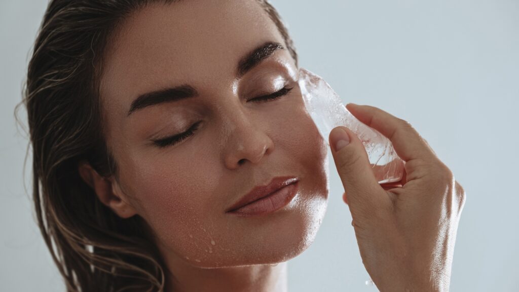 Žena hladi lice kockicom leda tokom ice facial tretmana
