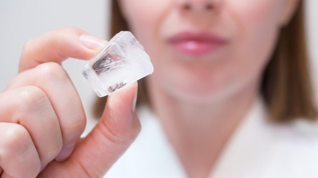 Žena drži kockicu leda ispred lica za ice facial tretman