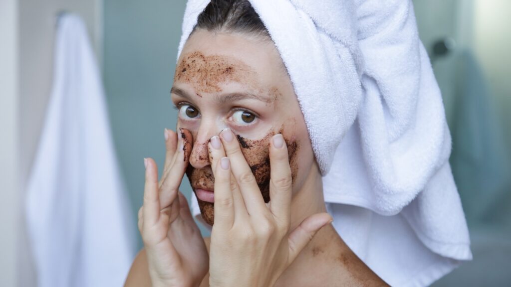 Žena u peškiru nanosi piling masku na lice tokom kućne nege