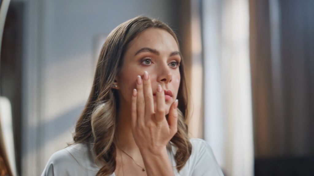 Žena nežno nanosi kremu sa SPF-om na lice.